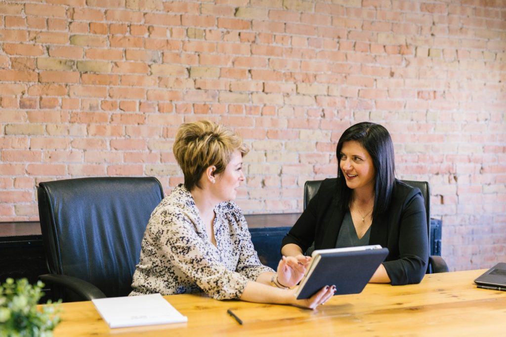 Two women in a meeting discussing on a tablet.